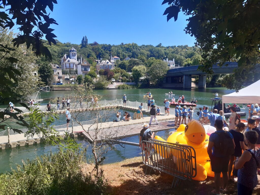 Une foule de baigneurs devant la Marne et un ponton, et un canard bouée géant, à Saint-Maur-des-Fossés, durant le Big Jump 2022